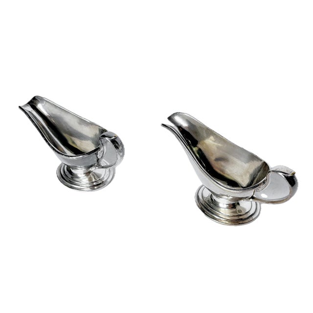 Pair antique English silver-plate creamers with spout and leaf style detailed handles. Marked.