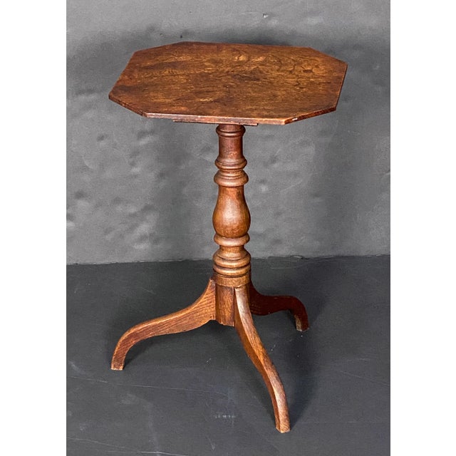 A fine English occasional table of oak, in the Georgian style, with an octagonal top atop a turned base and tripod legs.