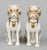 Pair of continental porcelain pug dogs sitting on their haunches, having separated legs and wearing gilded collars and bells.