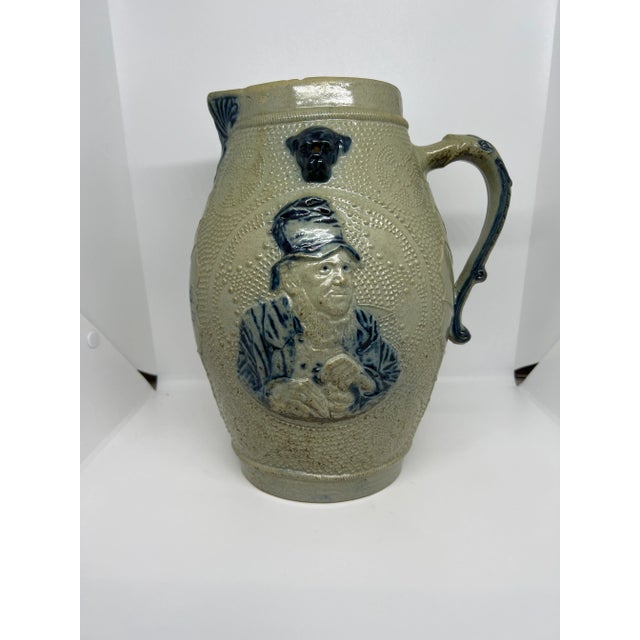 Antique salt-glazed pitcher from the 1800s. There is a bulldog on each side along with a male face. There are some chips...