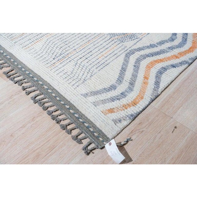 This hand knotted pile rug features a primary color palette of ivory, beige, cream, and white. Crafted from natural wool,...