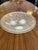 Round Art Deco-style valet tray featuring intricate engraved details of leaves and branches. The tray rests on three...