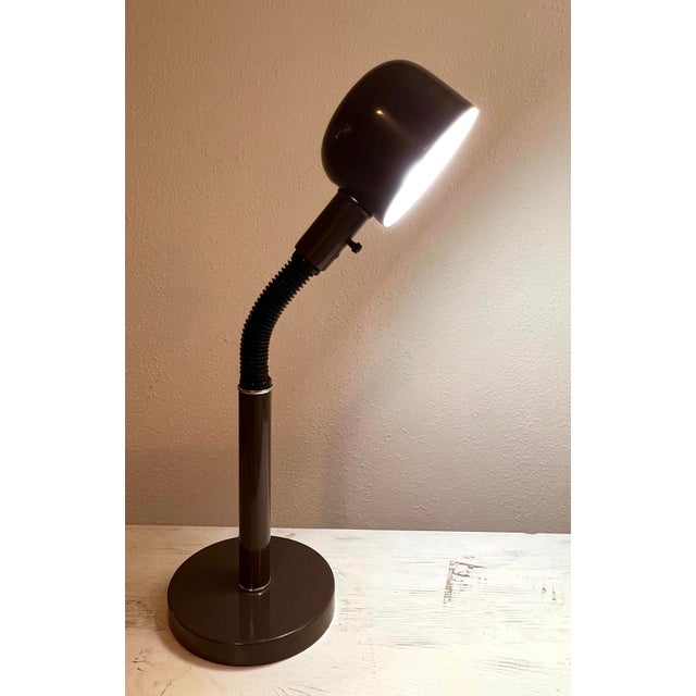 This Mod gooseneck lamp is by Lightolier featuring a brown metal base, hood shade, and the arm section is black flex...