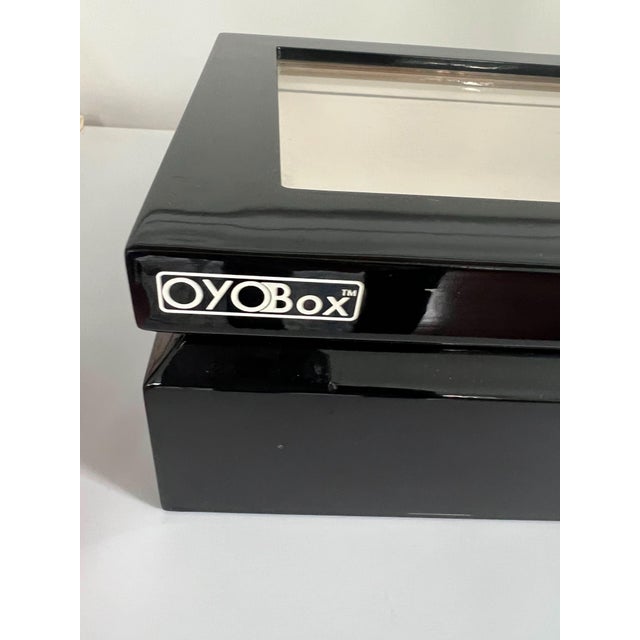 Designed for organizing and protecting fine eyewear, this OYOBox features a sleek, high-gloss black lacquer finish with a...