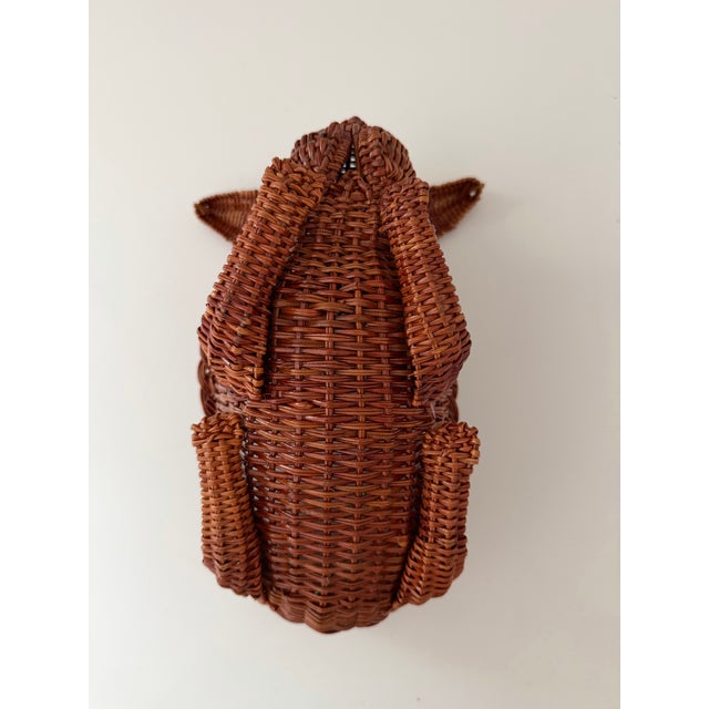 Woven rattan figure shaped like a reclining rabbit with a hollow basket section on its back.
