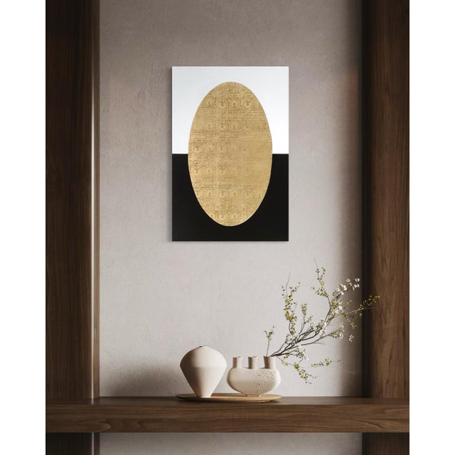 A softly patterned gold oval sits centered against a ground split cleanly in half, stark white above, deep black below....