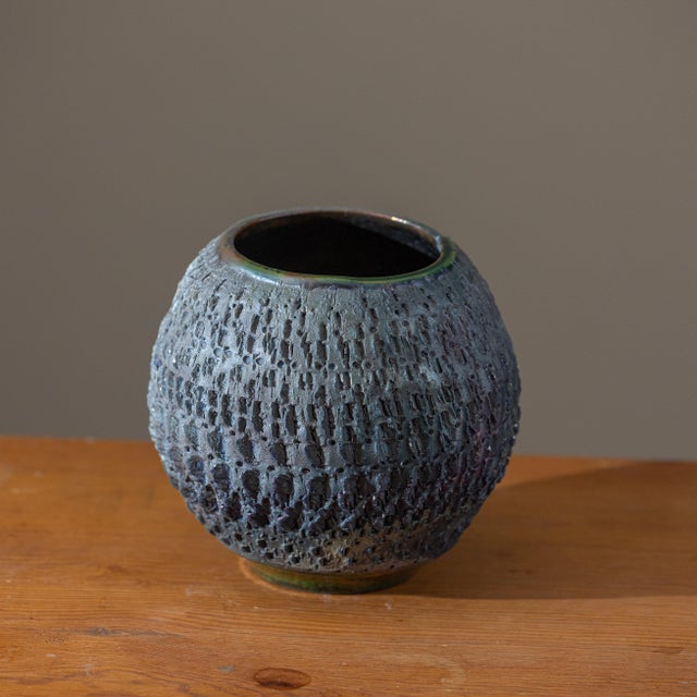 A beautifully executed hand-thrown studio pottery vessel by J. Lares, showcasing an intricately carved surface and a rich...