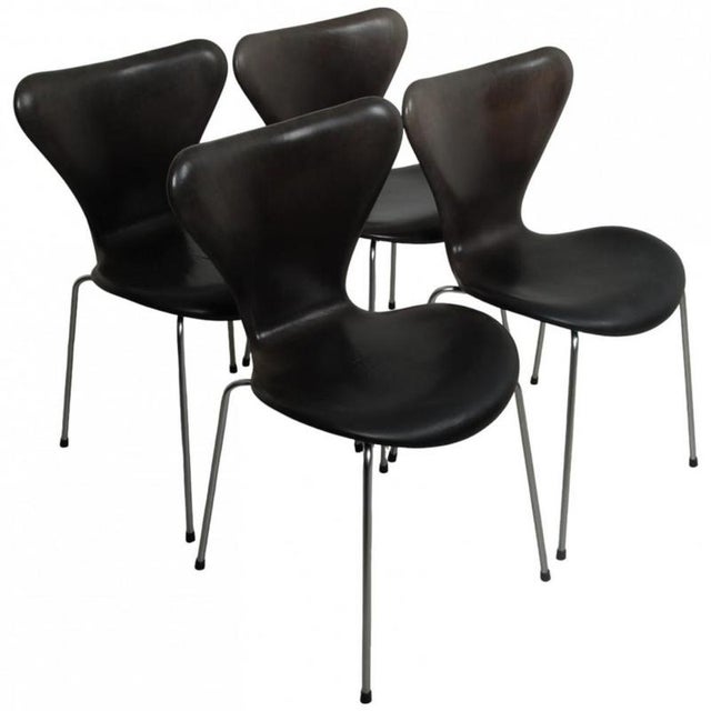 Set of 4 Arne Jacobsen Seven chairs. The chairs are upholstered in black anilin leather and with mat legs. The chairs are...