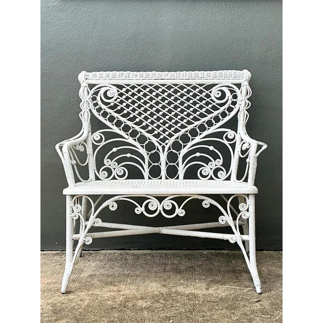 This vintage rattan bench is a showpiece of ornate, Victorian-inspired wickerwork, finished entirely in soft white paint....