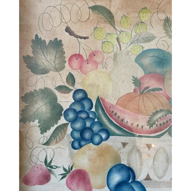 A lovely antique theorem painting of a colorful basket of fruit. Signed, Mary Ann. Framed in an antique wood frame.