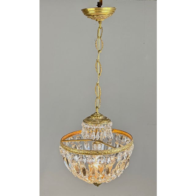 A gorgeous early 20th century French style basket crystal and brass chandelier with original chain and ceiling cap. A...