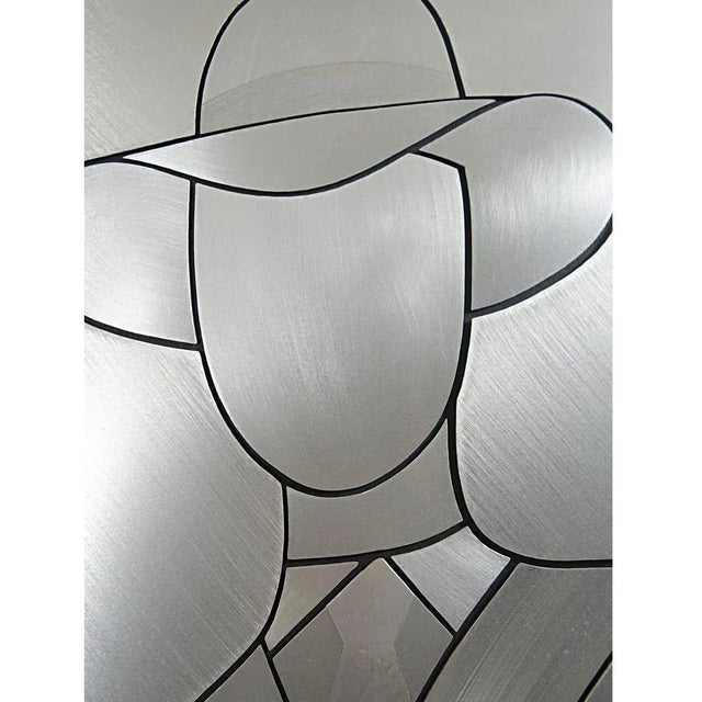 A stylized David Bowie in a piece of aluminum. His contours were created by cutting out his Silhouette in the material....