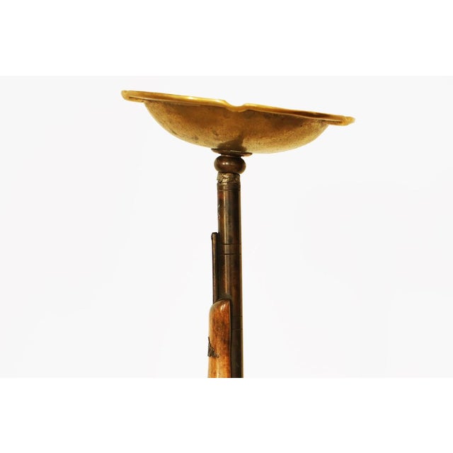 A striking and unusual mid-century floor ashtray featuring a sculptural rifle-form support with a gilt bronze dish above....