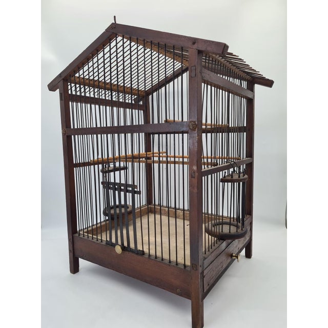An original, large wooden birdcage from the early 20th century, handcrafted from wood and iron rods. This model features a...