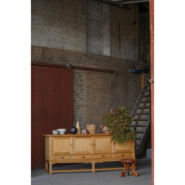 A charming low-profile sideboard crafted in oak and designed in the style of Henning Kjærnulf, Denmark, 1960s. The piece...
