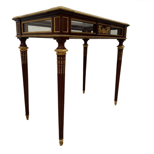 Louis XVI Style vitrine table in the manner of Francois Linke, the glass top rimmed by strips of gilt bronze over a case...