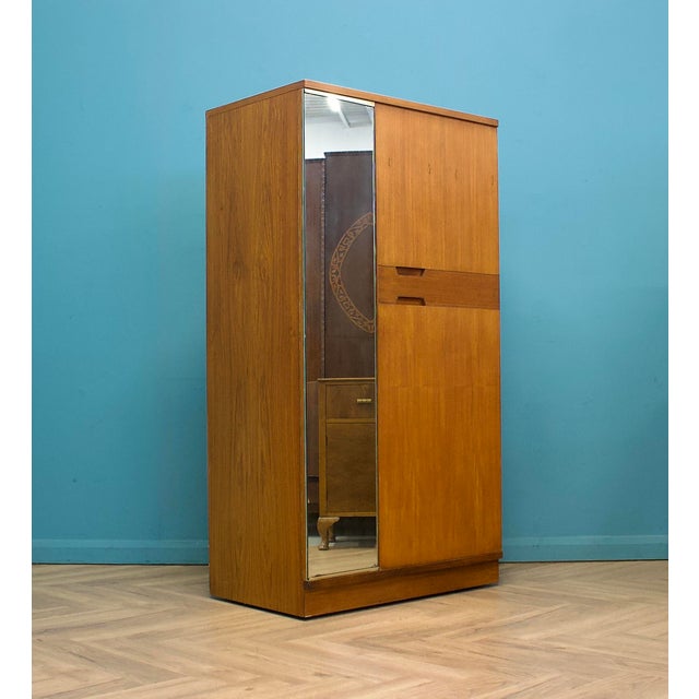 A mid century Uniflex wardrobe in warm teak veneer, with a clean front and recessed handles. Fitted with a mirrored door...