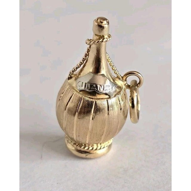 A charming vintage novelty pendant or fob crafted in 18-carat yellow and white gold and fashioned as a miniature bottle of...