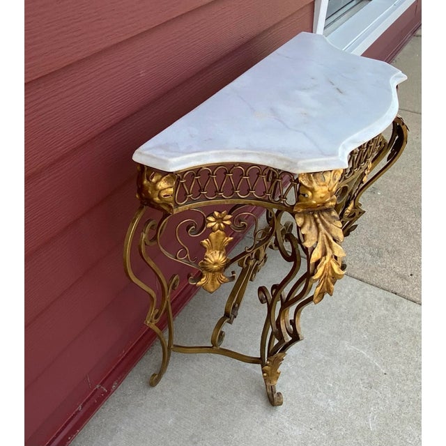 An extraordinary iron table of serpentine form, the scrolling frame with stylised foliate ornament and set with a marble...