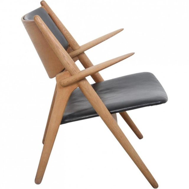 Hans wegner ch28 sawback lounge chair with a frame of oak and black leather upholstery. The chair is from the 1960s and...