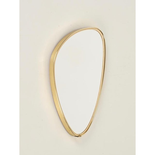 Elegant Italian Mid-Century wall mirror with brass frame featuring a refined asymmetrical organic shape. This charming...
