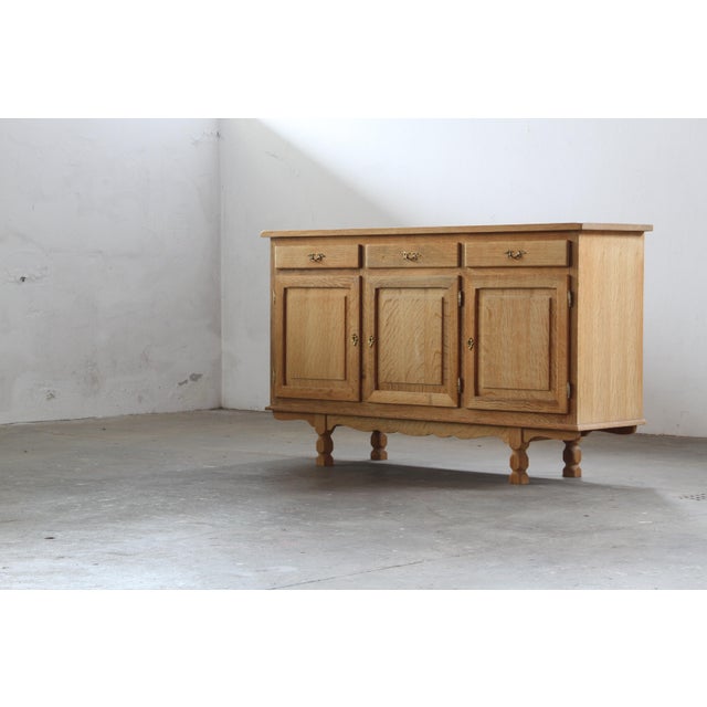 A sideboard crafted in the style of Henning Kjærnulf, showcasing oak construction with excellent craftsmanship. It...