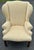 Generously proportioned wingback chair with pale yellow damask upholstery, block legs with stretcher, rolled arms and...