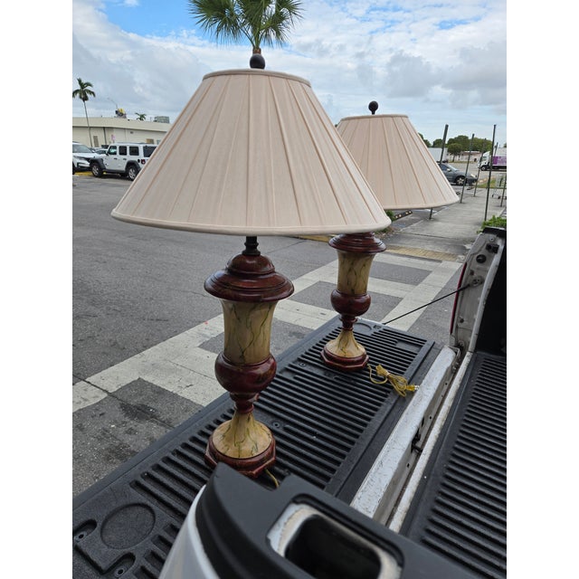 A pair of Theodore Alexander unsigned faux marble wood lamps sold as found showing slight wear commensurate w age.
