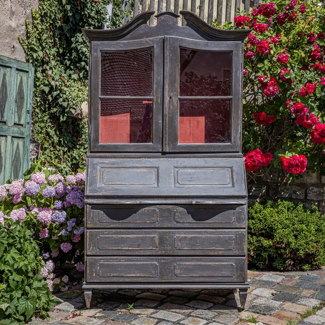 Baroque secretary cabinet featuring a two-door glazed display hutch above and a lower section with a slant-front writing...
