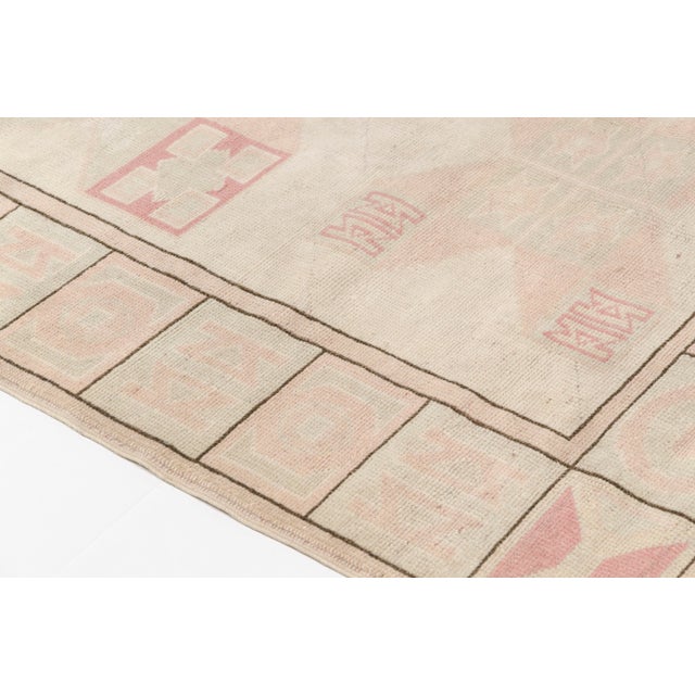 This is a vintage Turkish Oushak rug from the Mid 20th Century. The piece was hand-knotted.