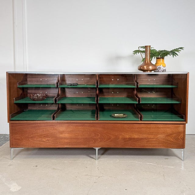 Crafted in Germany during the 1960s, this architectural display counter pairs rich mahogany veneer with a minimalist six-...