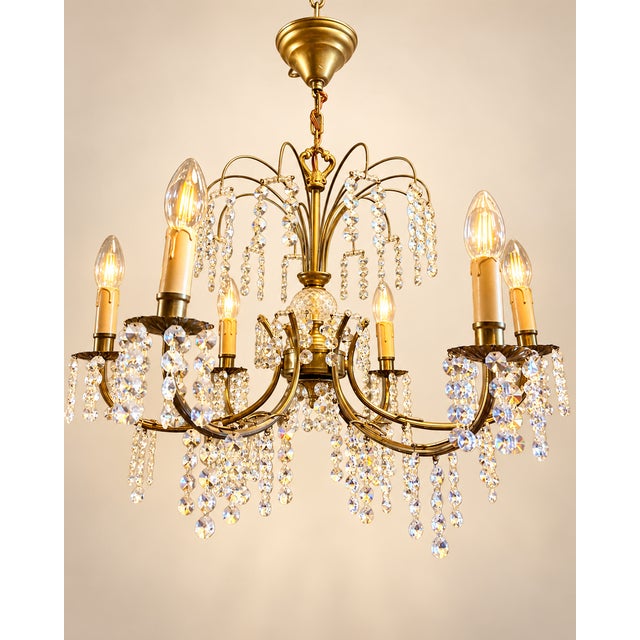 Elegant vintage crystal chandelier with 6 light points, featuring a warm brass/copper-colored frame and richly adorned...