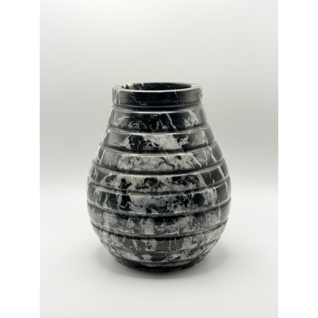 A beautifully hand-carved solid black marble vase featuring striking natural white veining and a sculptural ribbed...