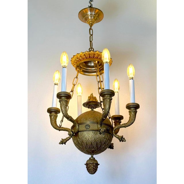 This antique chandelier is an example of the Empire style, constructed from heavy cast bronze with a finely chased ormolu...