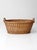 Antique wicker laundry basket with a wide oval form and integrated side handles, woven in alternating patterns that create...
