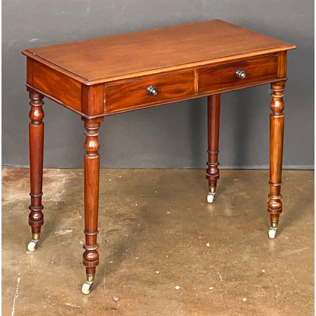 A fine English writing table or desk or side table of mahogany from the 19th century, featuring a moulded rectangular top...