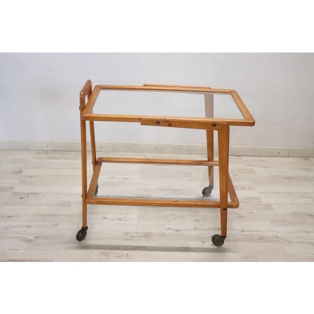 Rare 1950s Italian desgin serving bar cart. Made of beech wood equipped with two glass shelves and brass wheels for...