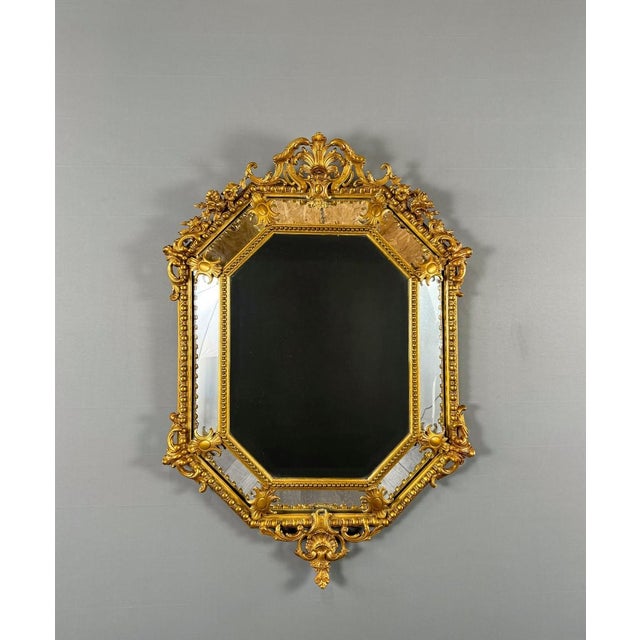 Superb antique octagonal mirror in finely carved and gilded wood, adorned with abundant rocaille decoration composed of...