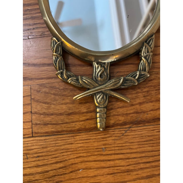 Lovely circa 1960's Wall mirror Trimmed in decorative and intricate brass tulip and ribbon design Mirror itself measures...