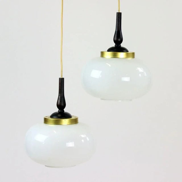 Beautiful, elegant ceiling pendant with two lights. Produced in 1960s in Czechoslovakia. The light has a wooden base on...