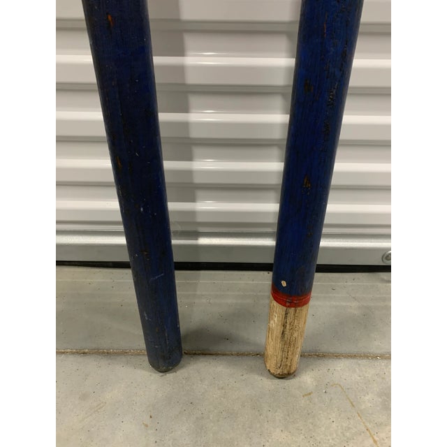 This pair of wooden oars features rectangular flat heads with cylindrical handles in colorful hand painted graphics.