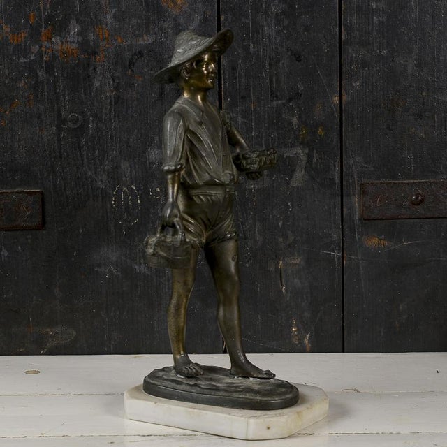 This charming bronze sculpture, depicting a young fisherman with baskets of fish and octopuses, evokes the authentic feel...