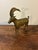 A striking vintage 1960s solid brass ram sculpture featuring intricate etched figural scenes across the body. The curved...
