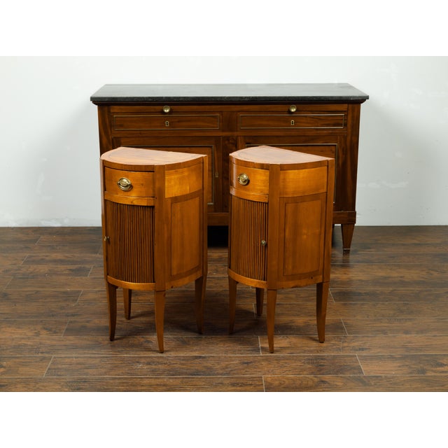 A pair of Italian walnut demilune bedside tables from the early 19th century, with tambour doors and single drawers....