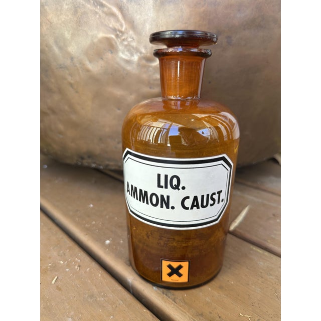 Authentic 1930s German amber glass apothecary bottle with original labeling. The front reads: “LIQ. AMMON. CAUST.” (Liquid...