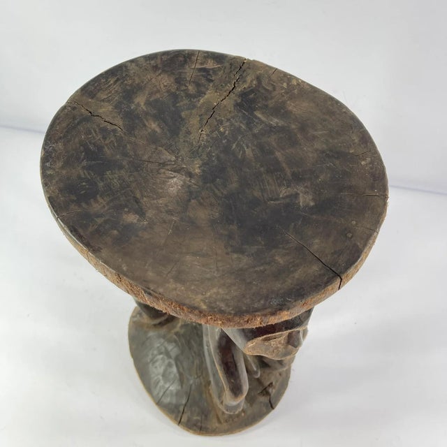 This finely carved Luba figural stool features two standing figures supporting the circular seat above, their hands...