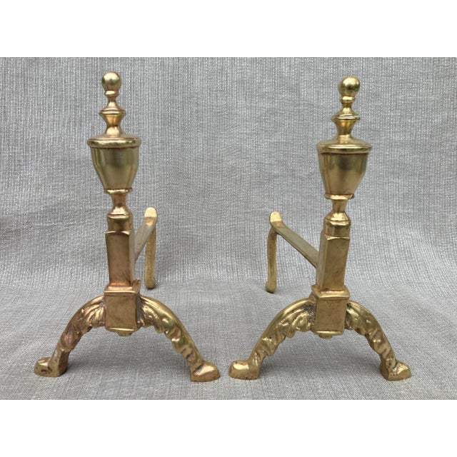 A pair of diminutive polished brass andirons. Turned elements at the top ending in ornate arched legs. Very good vintage...