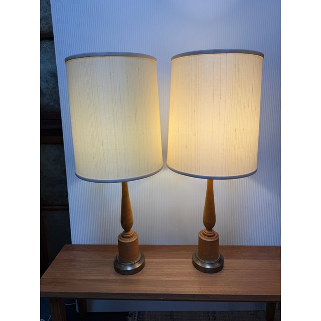 Design Plus Gallery presents a Pair of Walnut Table Lamps from the Mid 20th Century. They are both very tall with shaped...