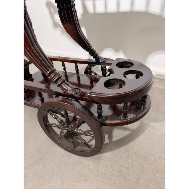 Elegant mahogany drinks trolley featuring beautifully carved details, turned spindle galleries, and large decorative...
