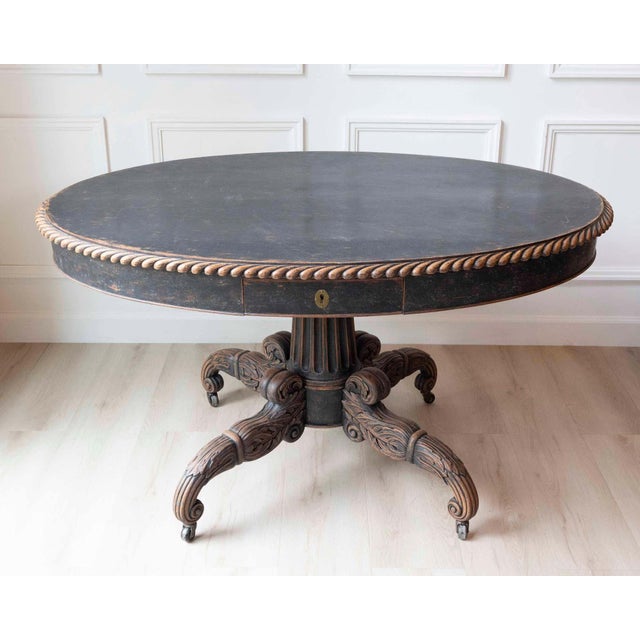 A striking Swedish Empire oval center table, circa 1830, distinguished by its bold architectural form and richly carved...